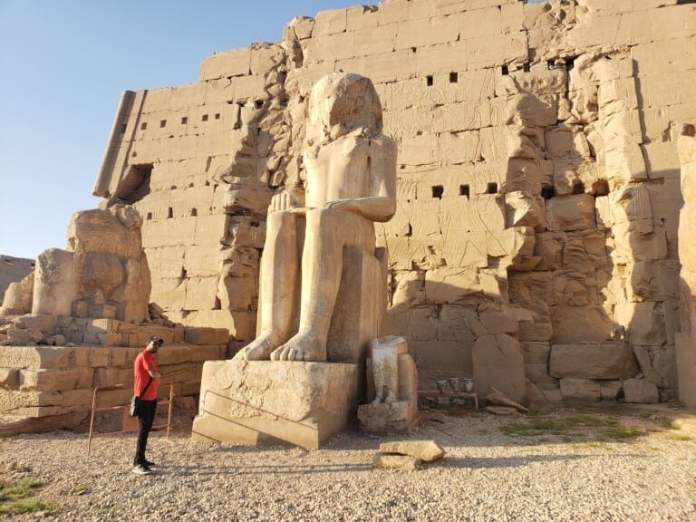 A person posing next to a gigantic monument in Luxor Temple, Egypt
