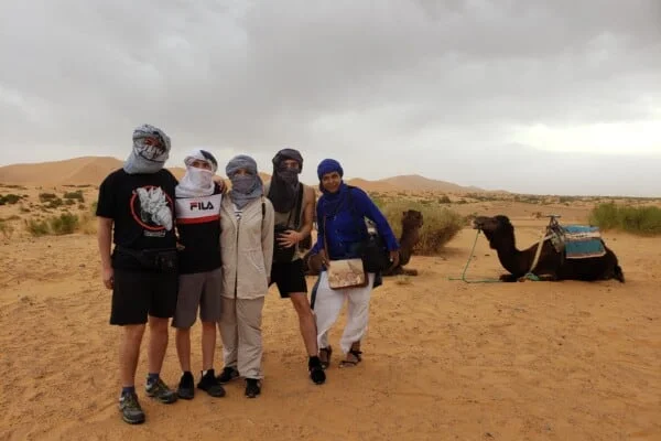 Travelers at Merzouga Sahara Desert, with camels in the background