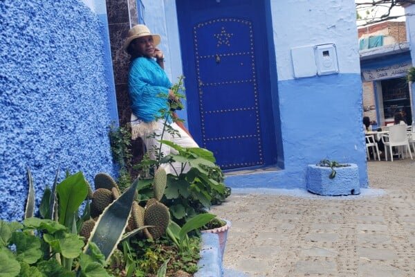 A woman posing in a street alley in the Blue City of Chefchaouen, Morocco.
