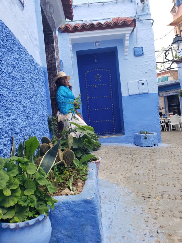A woman posing in a street alley in the Blue City of Chefchaouen, Morocco.