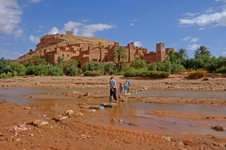 Group of people crossing a shallow river to Ait BenHaddou Kasbah in Ouarzazate
