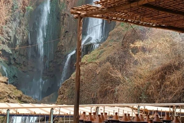 Tagine dishes in display against the view of Ozoud Falls, Morocco