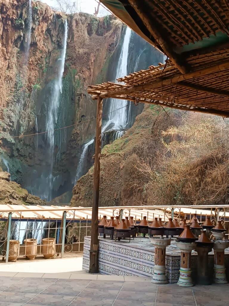Tagine dishes in display against the view of Ozoud Falls, Morocco