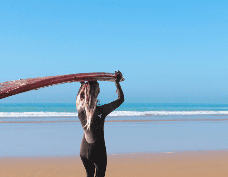 A surfer carrying a surfboard, heading to Taghazout beach in Morocco